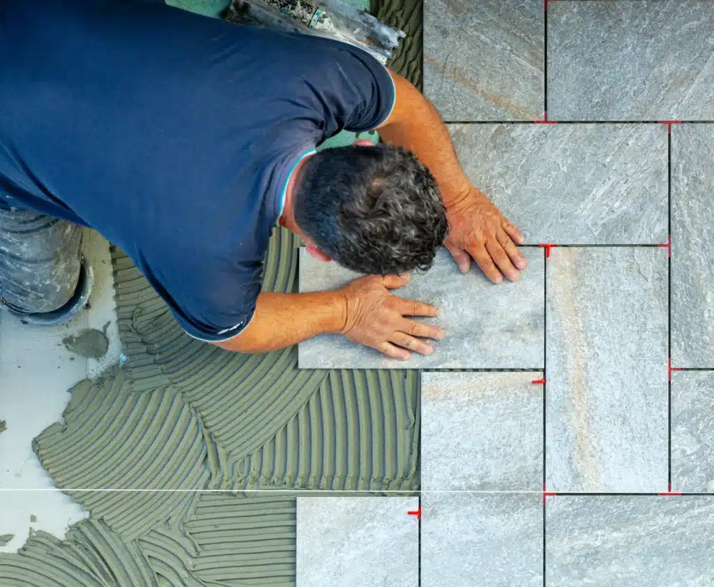 Natural stone flooring installation Worker setting stone tile as a flooring contractor would on a prepared floor